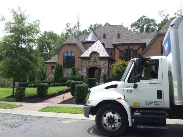 A moving truck parked in front of a large house